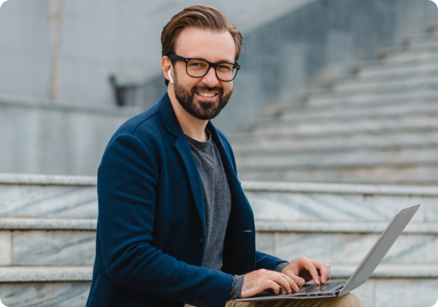 handsome-smiling-bearded-man-glasses-working-laptop
